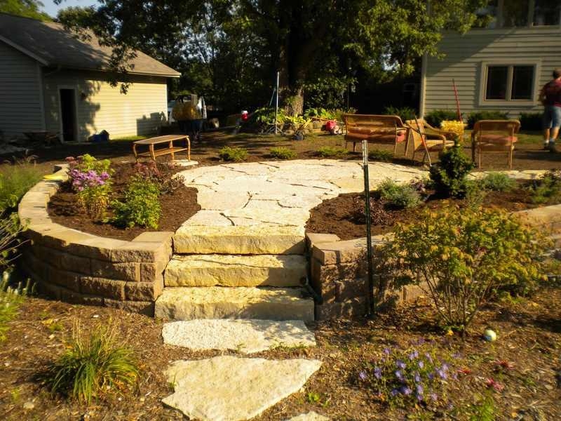 A patio is created by a short retaining wall and paved stone